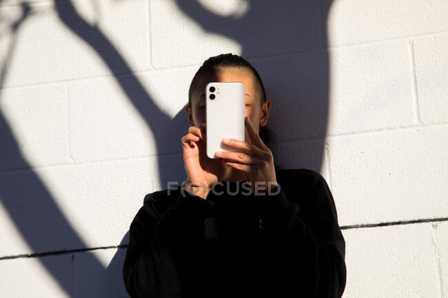 Mujer usando el teléfono celular al aire libre con sombra de árbol - foto de stock