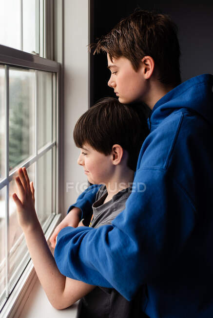 Dos chicos mirando por la ventana con caras tristes - foto de stock