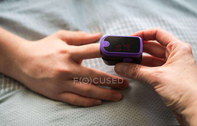 Primo piano di una mano che mette un pulsossimetro al dito di qualcuno. — Foto stock
