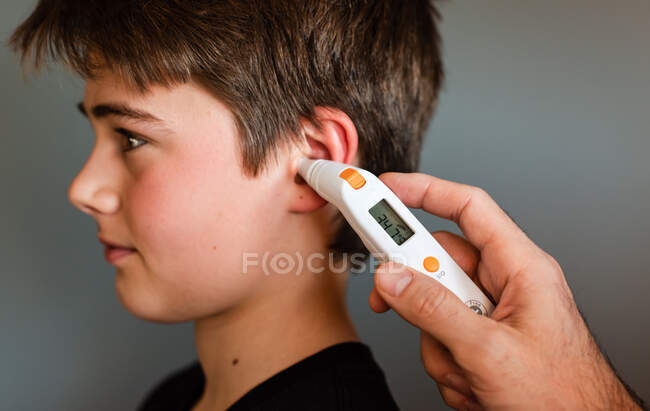 Твін-хлопчик отримує температуру за допомогою світлового термометра.. — стокове фото