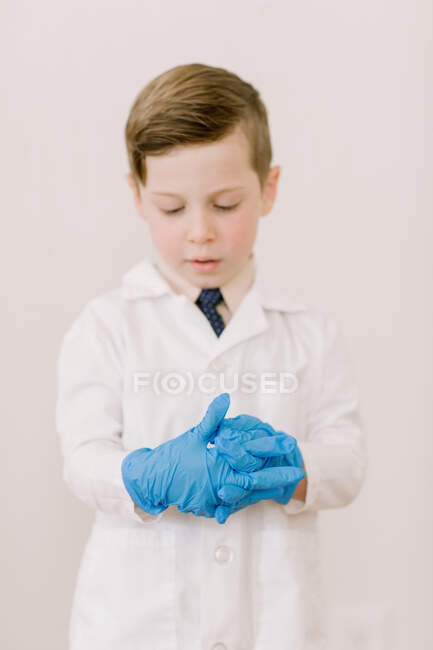 Child in labcoat putting on gloves — Stock Photo