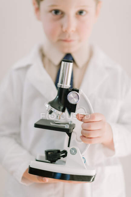 Ребенок в плаще держит научный микроскоп — стоковое фото