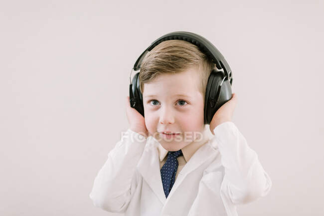 Niño en abrigo con auriculares - foto de stock