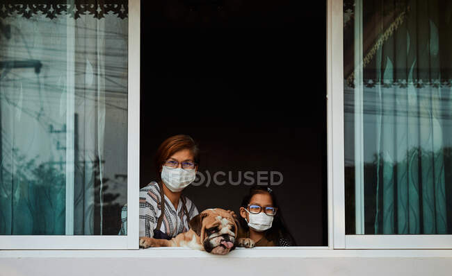 Madre e hija con su perro se quedan en casa durante la epidemia de COVID-19 - foto de stock