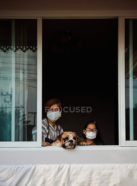 Мати і дочка з собакою залишаються вдома під час епідемії COVID-19. — стокове фото