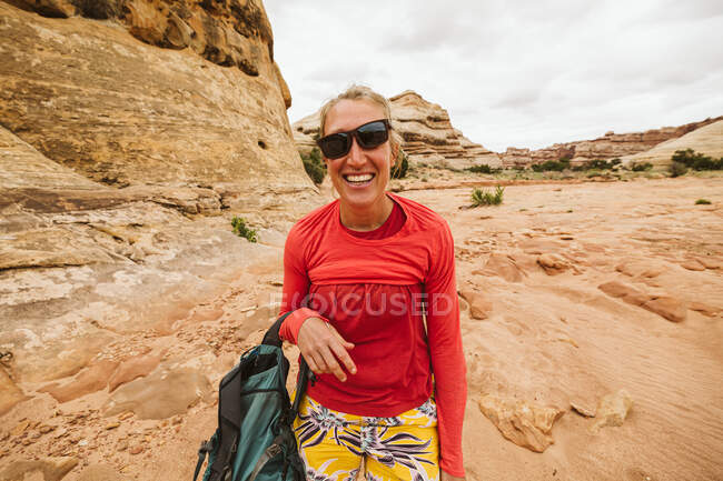 Desert hiker with slanted sunglasses and messup up shirt laughing — Stock Photo