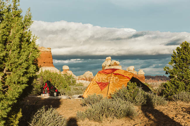 Tenda arancione e zaino di installazione in mezzo al deserto arbusto in utah — Foto stock