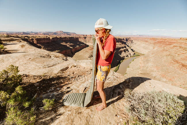 Female camper blows up sleeping pad at a campsite above grand canyon — Stock Photo