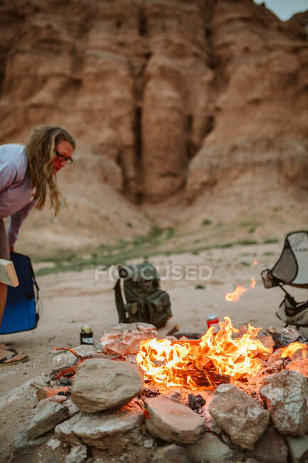 Femme debout près du feu de camp dans le désert — Photo de stock