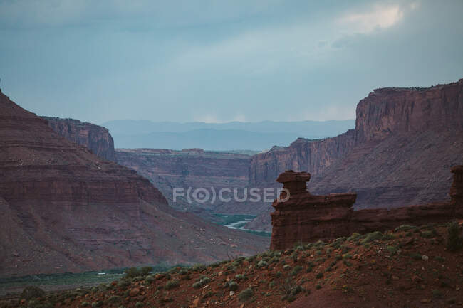 View of red rock sandstone butte formation rising above colorado river — Stock Photo