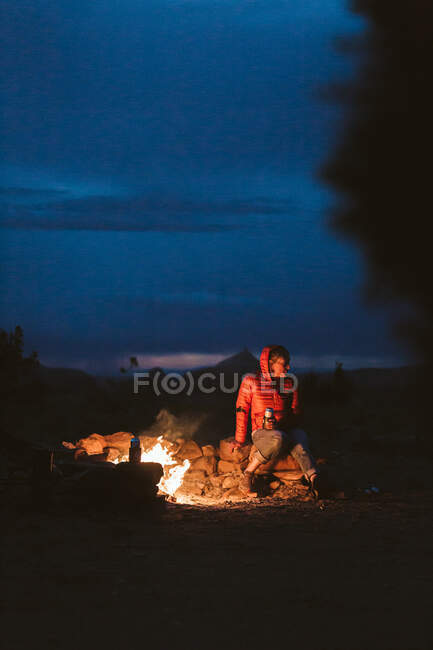 Femme assise sur un feu de camp dans les montagnes. — Photo de stock