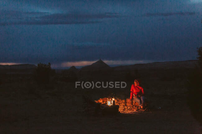 Donna seduta su un falò in montagna. — Foto stock