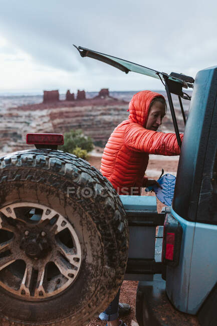Frau in orangefarbenem Anzug greift im Camp in das Heck ihres Jeeps — Stockfoto