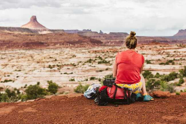 Una joven de rojo sentada en el desierto - foto de stock