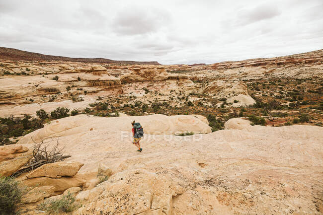 Una joven de rojo caminando por el desierto - foto de stock