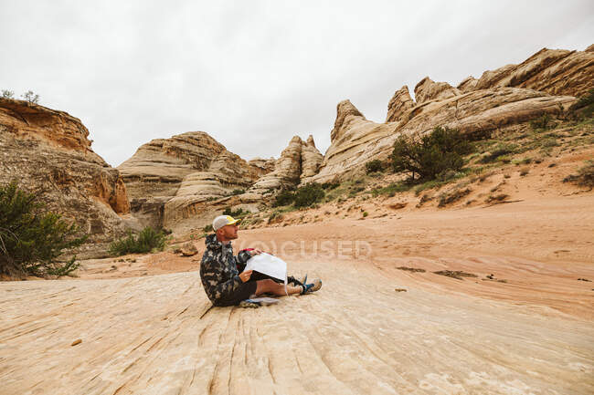 Homem sentado no chão arenoso no deserto — Fotografia de Stock