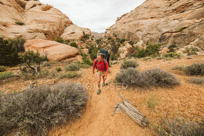 Junge Wanderin in Rot mit Rucksack auf Wanderweg — Stockfoto