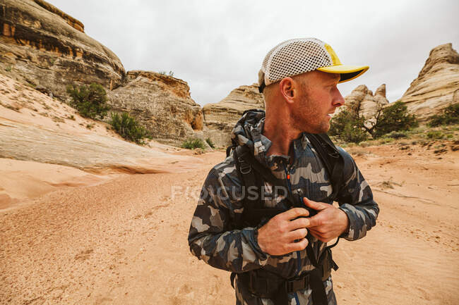 Mann in Tarnkleidung mit Rucksack in der Wüste — Stockfoto