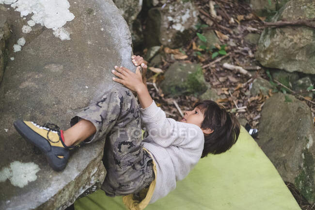 Little boy climbing a boulder outdoors — Stock Photo