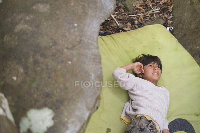 Little boy rests on a crashpad next to a rock — Stock Photo