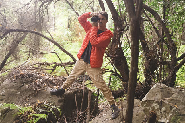 Молодий чоловік фотографується в дощовому лісі — стокове фото