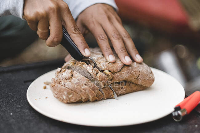 Closeup of women hands cutting bread outdoors — Stock Photo