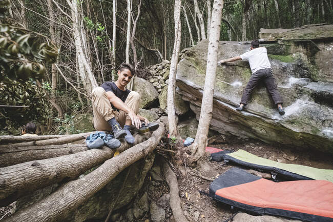 Zurückgezogene Ansicht eines Mannes, der klettert, während ein anderer Schuhe anzieht — Stockfoto