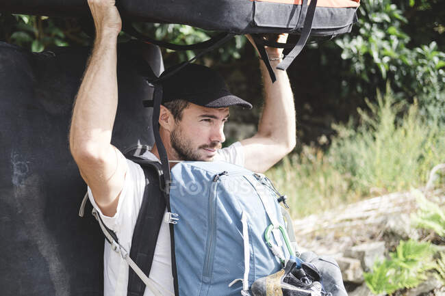 Retrato de un escalador que lleva un crashpad y mochilas - foto de stock