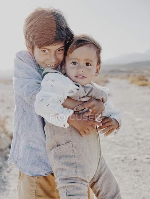 Портрет двух детей, обнимающихся в пустыне — стоковое фото