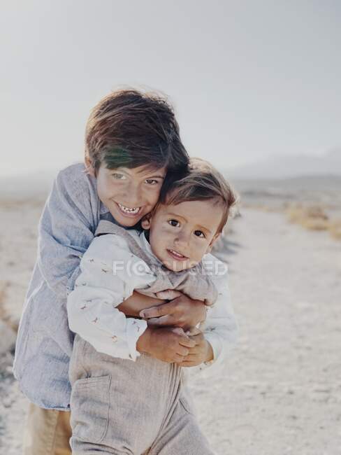 Retrato de dos niños abrazándose en el desierto - foto de stock