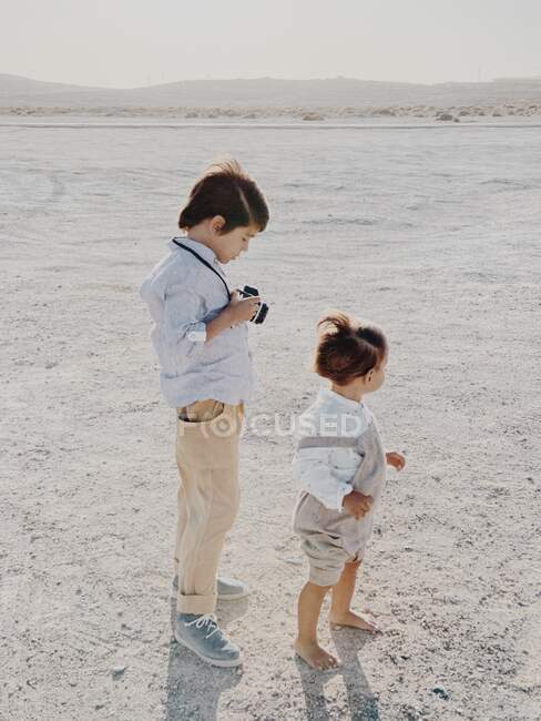 Retrato de uma criança segurando uma câmera como outra criança fica ao lado dele — Fotografia de Stock
