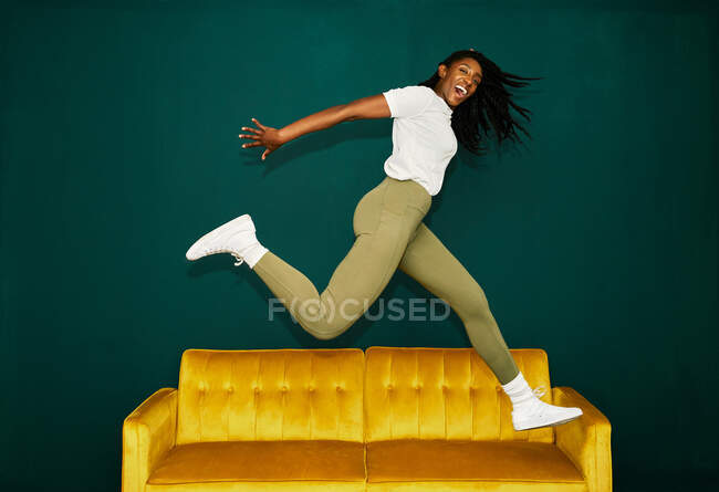 Junge schwarze Studentin springt über gelben Reisebus. — Stockfoto