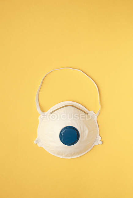Маска для обличчя або пилова маска або фільтруючий респіратор для обличчя - захист від забруднення повітря або грипу або спалаху вірусу на жовтому тлі — стокове фото