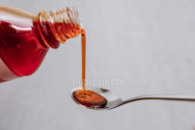 Poring maple syrup in spoon on light background — Stock Photo