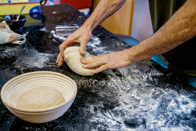 Человек месит тесто из теста для хлеба на домашней кухне — стоковое фото