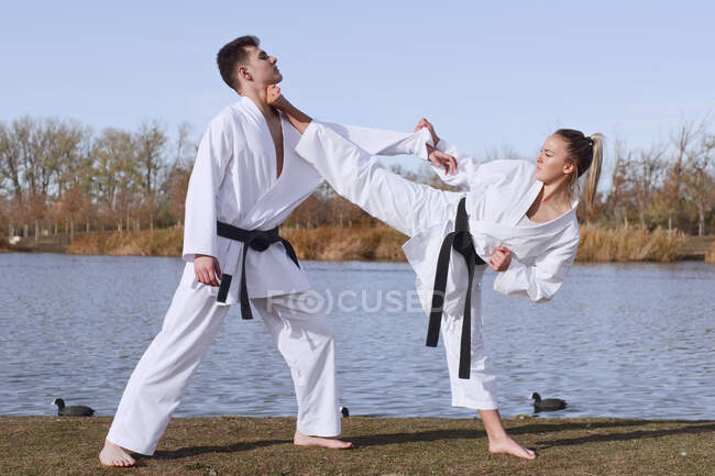 Молода дівчина і молодий хлопчик карате експерти практикують і борються — стокове фото