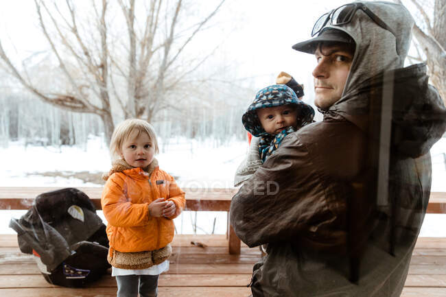 Young family visits quarantined uncle and looks through window glass — Stock Photo