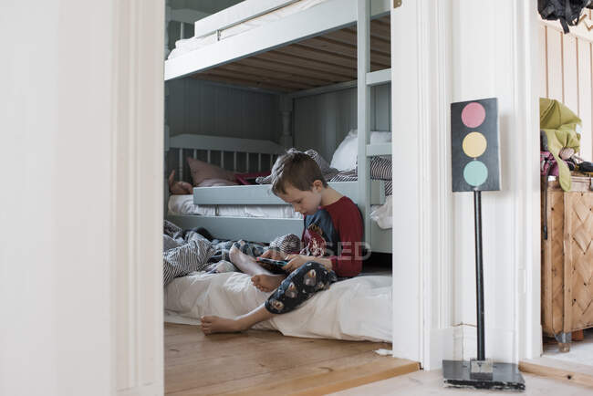 Мальчик сидит в своей спальне и играет в компьютерные игры в пижаме — стоковое фото