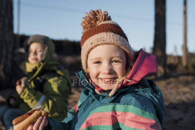 Portrait d'une jeune fille mangeant un hot dog près d'un feu de camp en Suède — Photo de stock