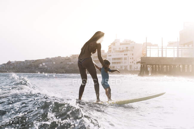 Mãe e filho surfando uma pequena onda no mar — Fotografia de Stock
