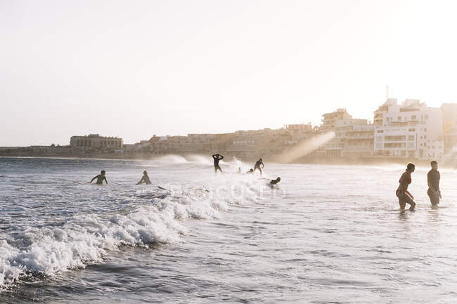 Vista para trás de surfistas e pessoas na praia ao pôr-do-sol — Fotografia de Stock