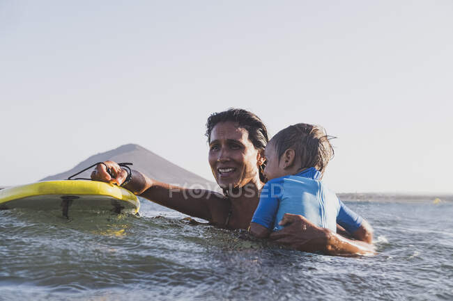Madre e figlio facendo surf su una piccola onda in mare — Foto stock
