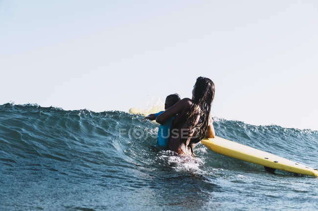 Mère et fils surfant sur une petite vague en mer — Photo de stock