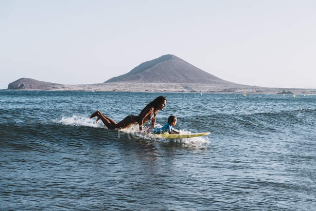 Mutter und Sohn surfen auf einer kleinen Welle auf dem Meer — Stockfoto