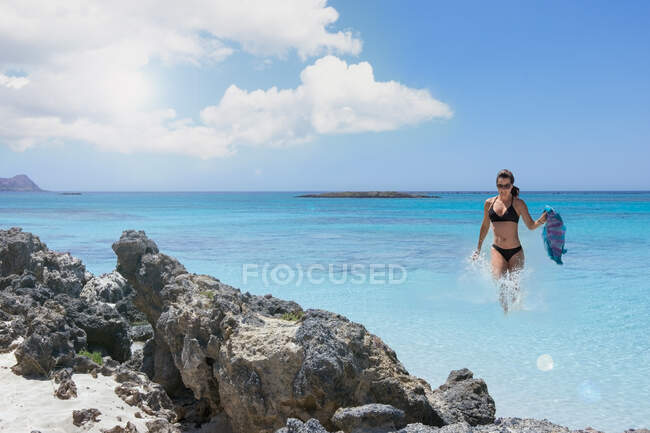 Paesaggio con donna al mare scogli spiaggia e turchese chiaro — Foto stock