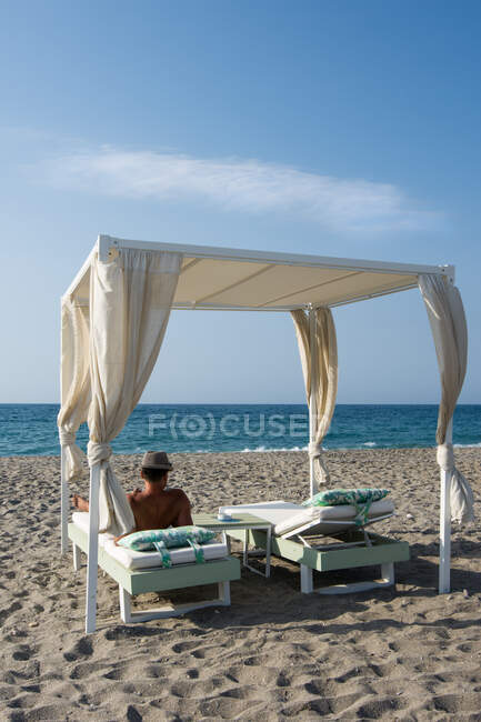 Homem descansa na sombra na praia da Grécia no verão — Fotografia de Stock