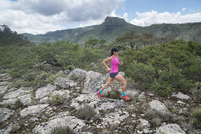 One girl with pink t shirt trail running on a high rocky surface — Stock Photo