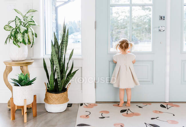 Little girl looking out the door — Stock Photo