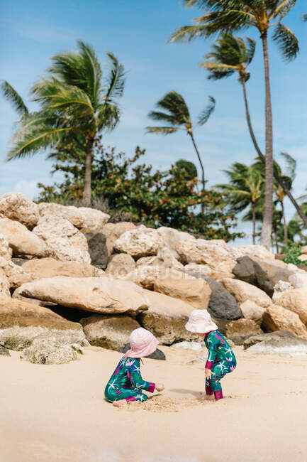 Hermanas jóvenes jugando en la playa hawaiana - foto de stock