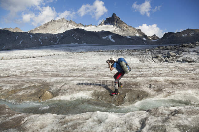 El hombre toma fotos en el glaciar Snowbird, montañas Talkeetna, Alaska - foto de stock